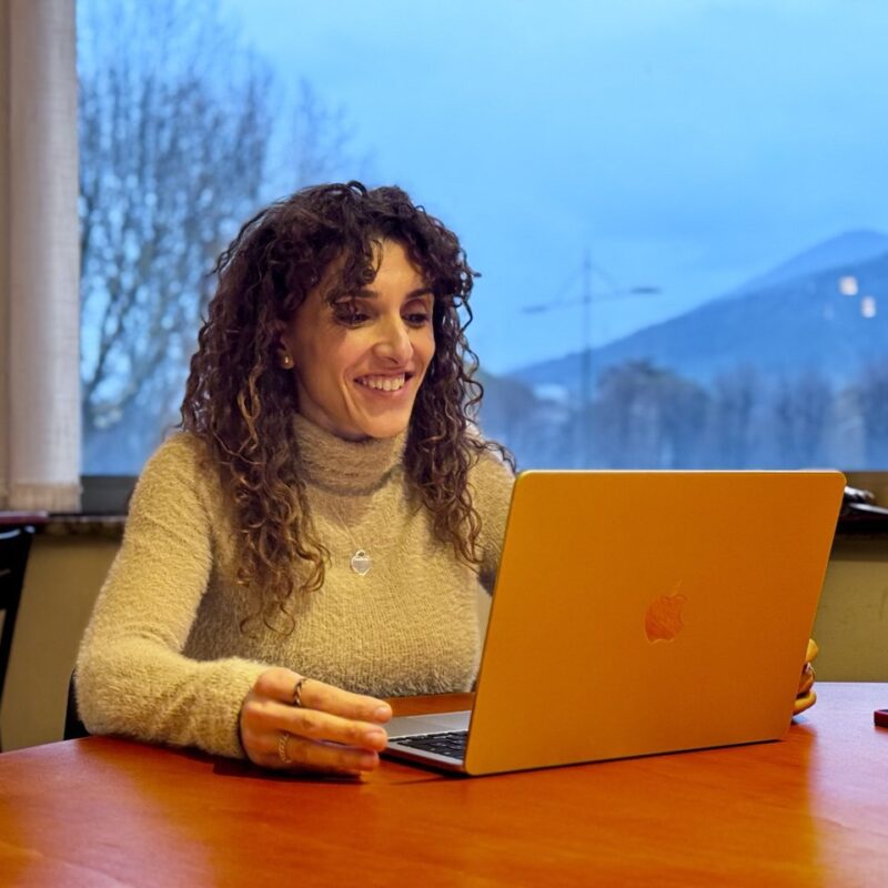 "Federica Romagna, Career Coach e consulente di carriera sorride davanti al pc durante una sessione di career coaching. Aiuta i professionisti e le professioniste a cambiare lavoro senza sapere cosa fare e a trovare la propria identità.